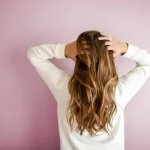 Woman with wavy hair against pink wall.