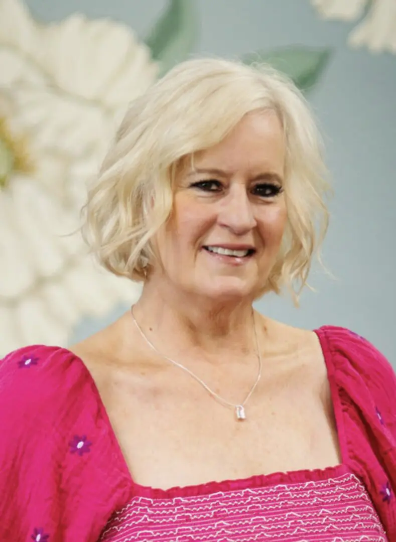 Woman smiling in a bright pink dress.